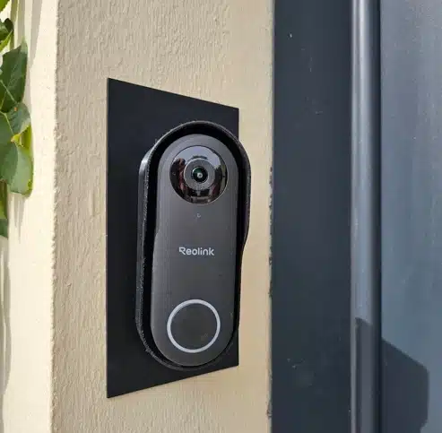 Gros plan sur la sonnette vidéo connectée Reolink PoE montée sur plaque de finition noire et support pare-pluie